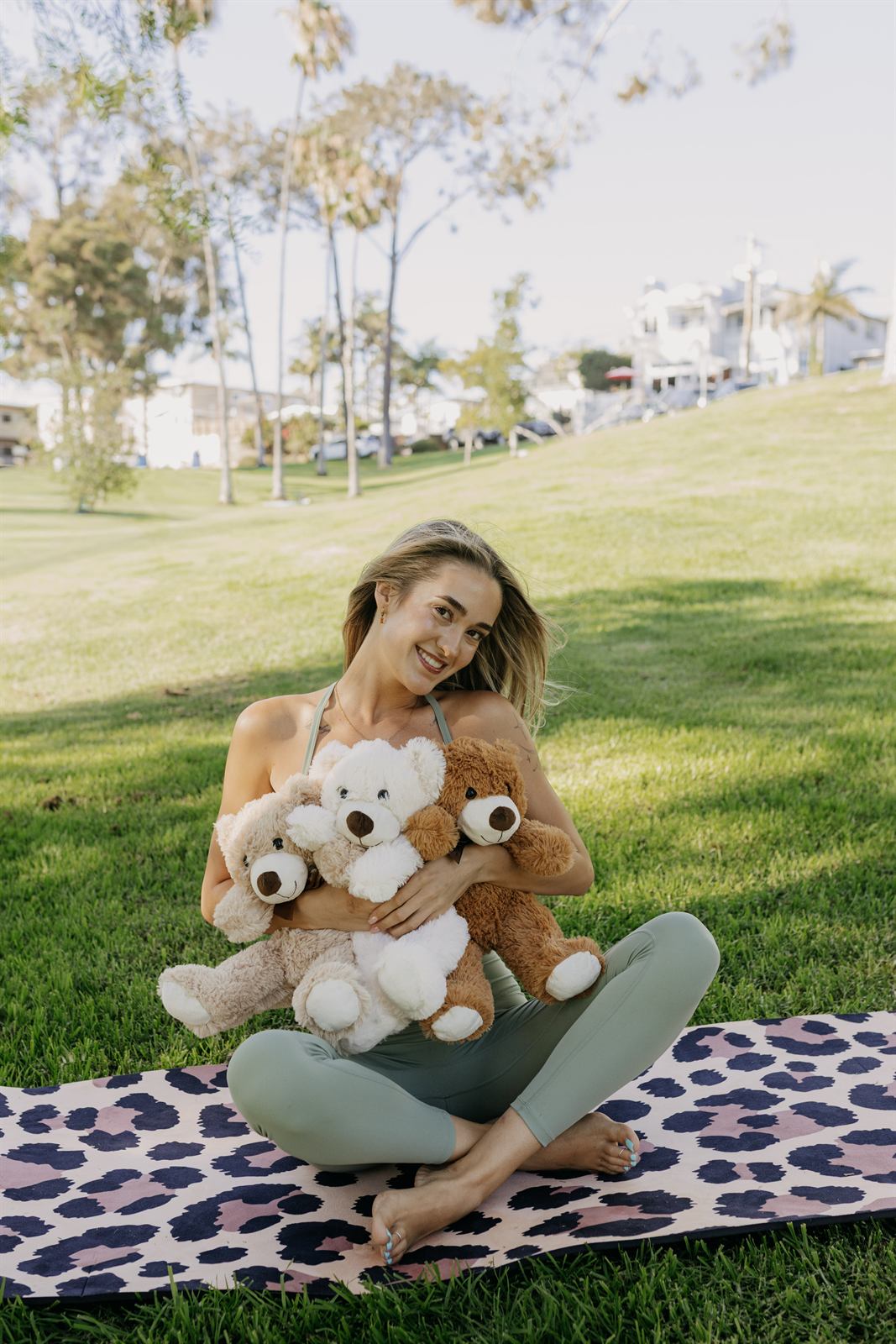 Teacher hugging two teddy bears on a yoga mat