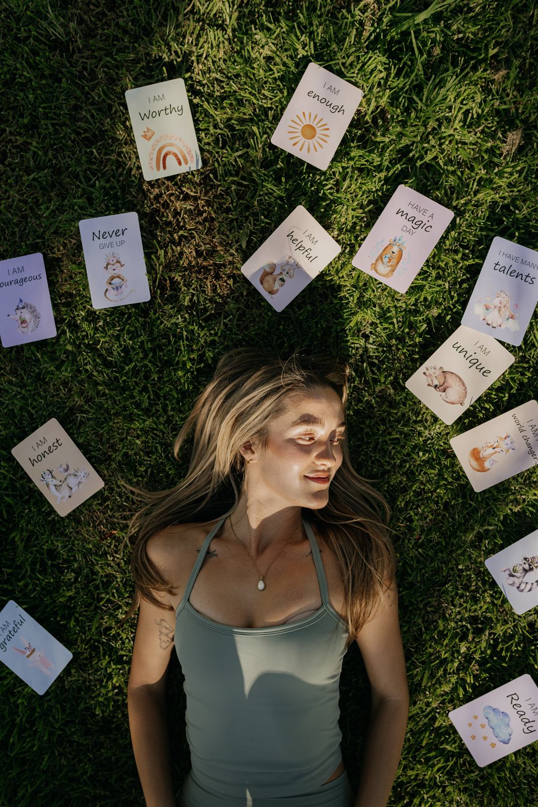 Teacher lying in the grass surrounded by affirmation cards