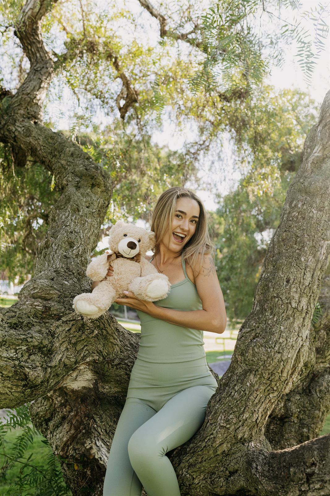 Teacher sitting on a tree branch holding a teddy bear